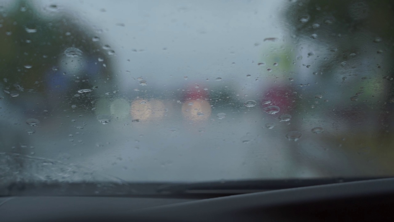 在城市街道上用雨刷清除汽车挡风玻璃上的雨滴视频素材