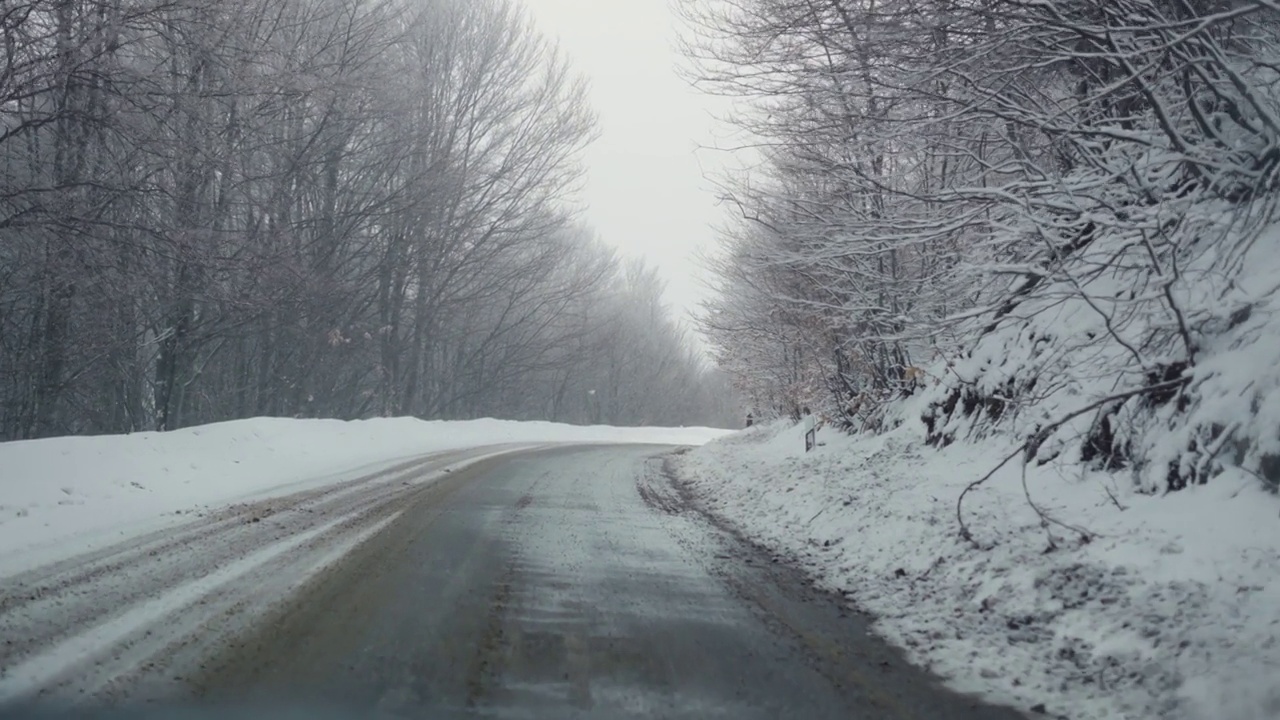 在冰天雪地的山林乡村道路上开车的Pov视频素材