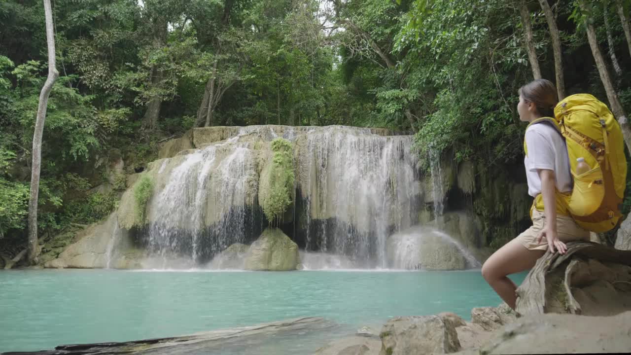 一个亚洲少女踏上了在泰国丛林中发现绿松石瀑布的旅程。视频素材