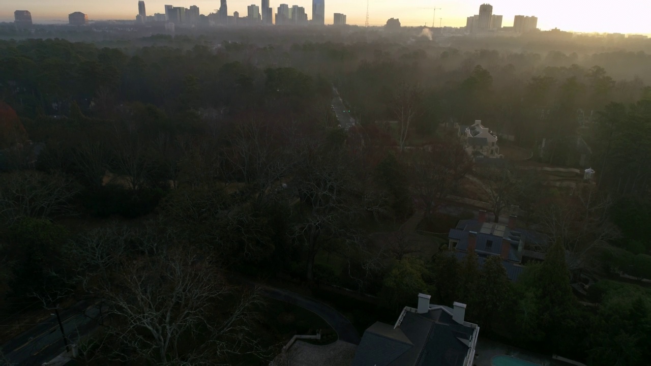 空中倾斜拍摄的现代建筑在城市的天空，无人机在日落时向后飞过树木-亚特兰大，乔治亚州视频素材