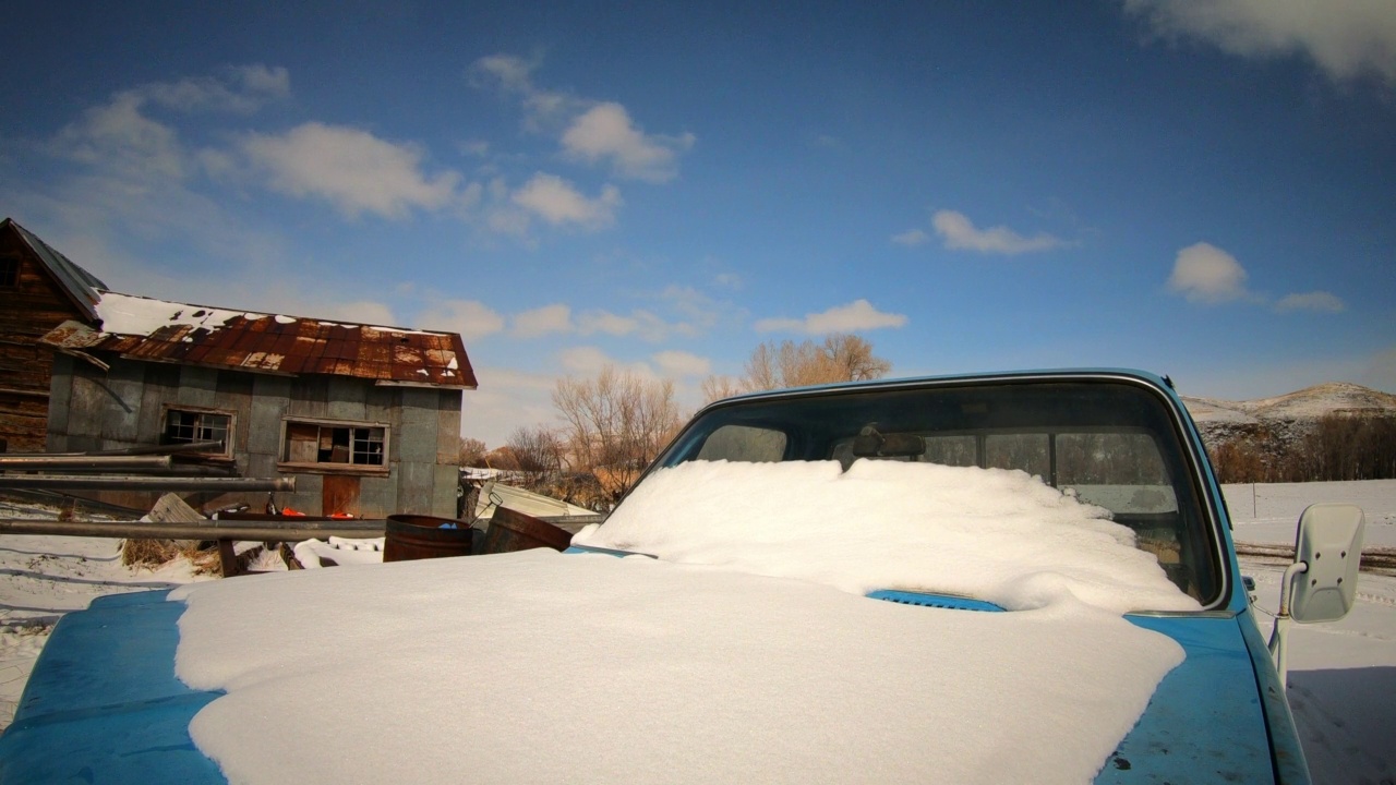 在蒙大拿州的黄石公园，空中的云层下，雪融化在汽车引擎盖和挡风玻璃上的延时锁定镜头视频素材