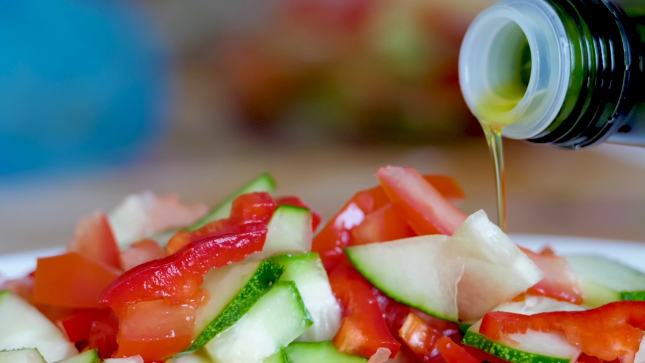 蔬菜新鲜沙拉食物健康餐地中海厨房素食橄榄油。把橄榄油倒在新鲜的沙拉上。近距离健康午餐，多彩食物洋葱黄瓜萝卜。慢动作视频素材