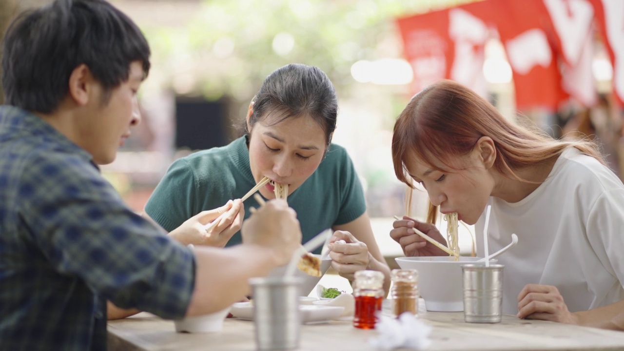 三个朋友在吃日式面条(拉面)。视频素材