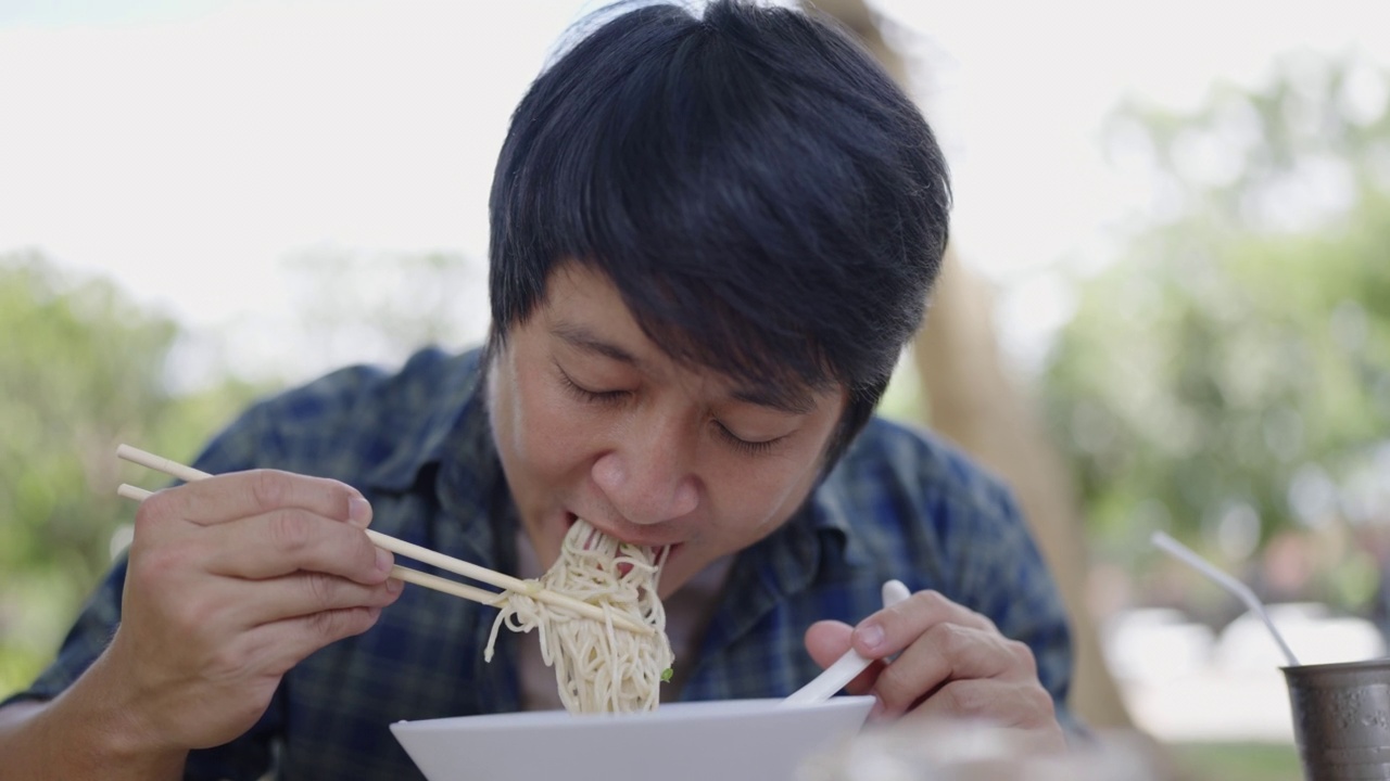 近距离拍摄的亚洲人吃和喝拉面在街头食品市场视频素材