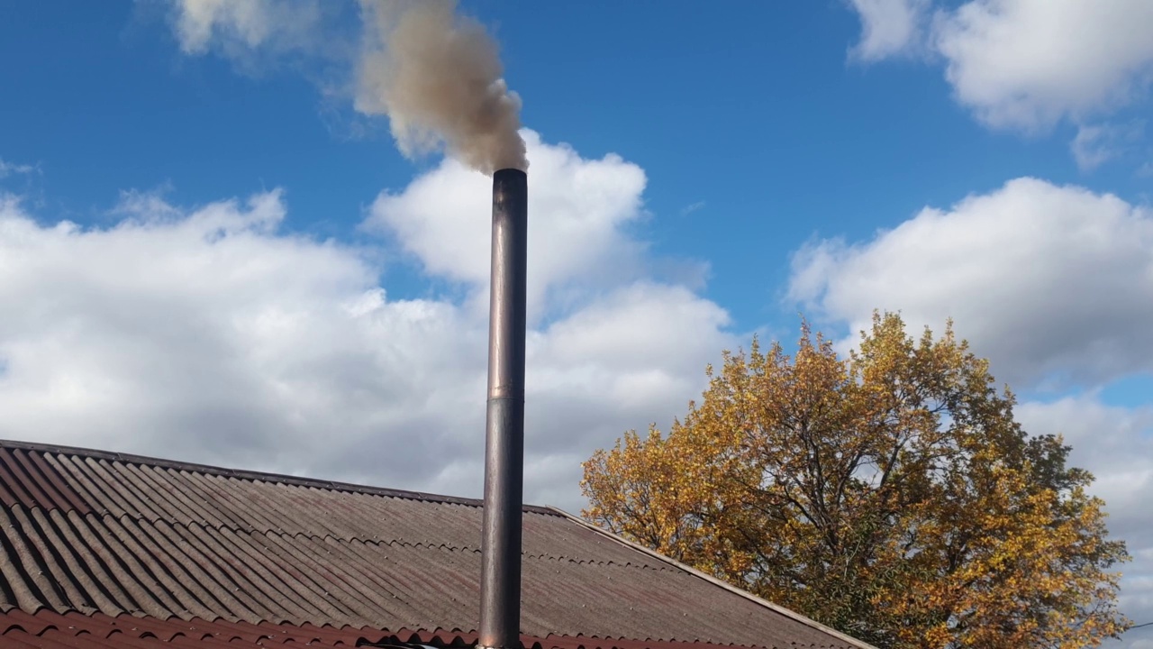 烟囱冒出的烟对着天空，用煤取暖的小屋，环境污染和能源危机视频素材