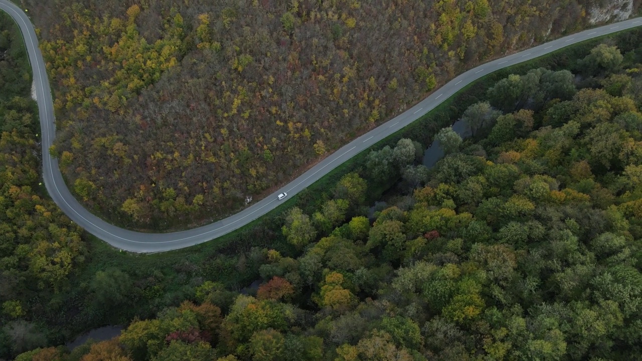 汽车行驶在道路上，在秋天的日子重型车辆运输旅行汽车驾驶假期的概念上，沥青自上而下的空中无人机视图视频素材