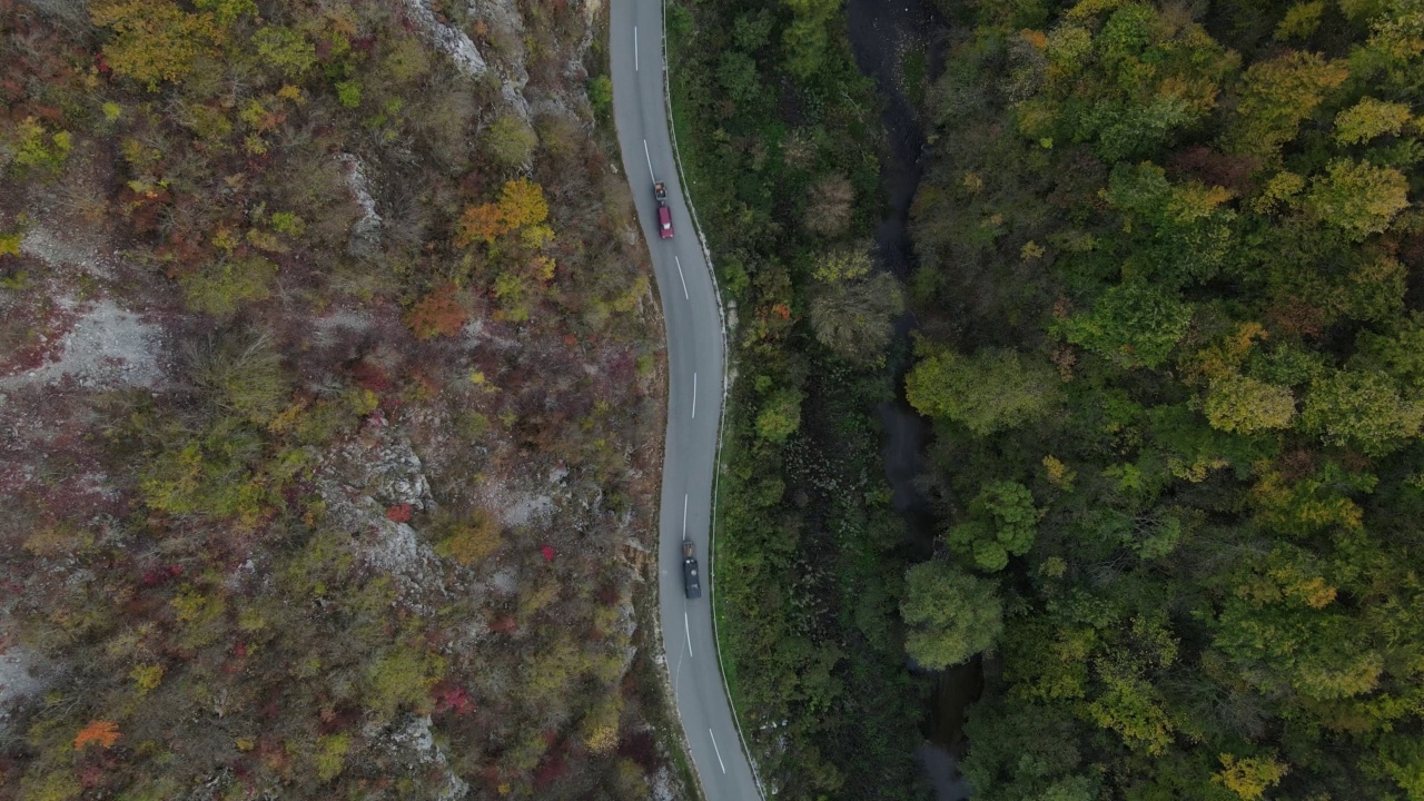 汽车行驶在道路上，在秋天的日子重型车辆运输旅行汽车驾驶假期的概念上，沥青自上而下的空中无人机视图视频素材