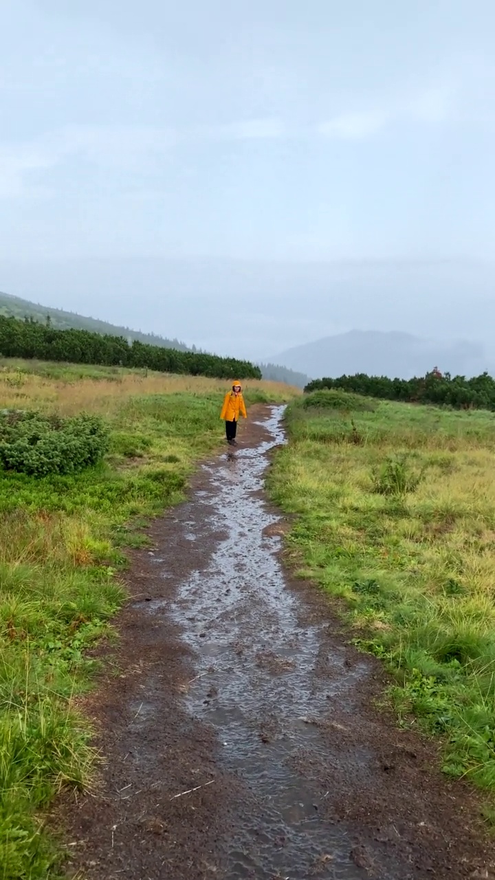 第一人称，走在湿山尾女人在黄色雨衣前面视频素材