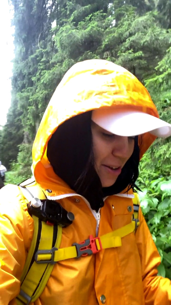 快乐的女人穿着黄色雨衣在雨中徒步视频素材