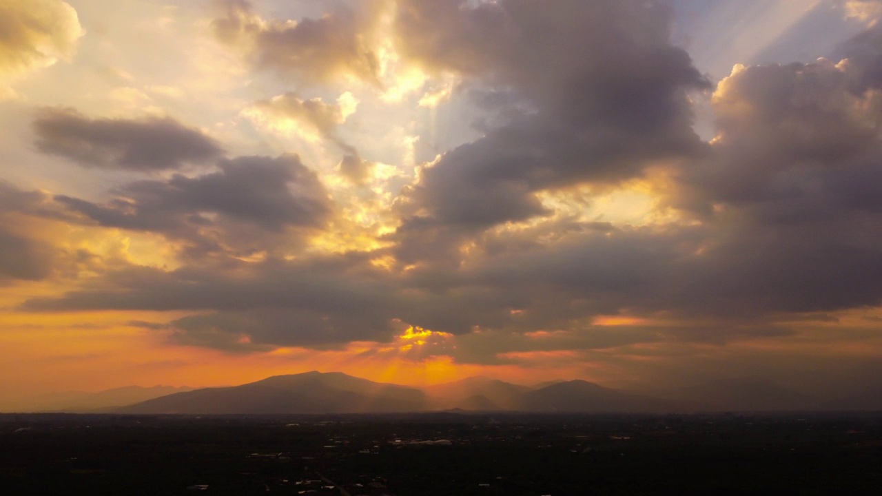 夕阳的天空与金色的阳光映衬着山景的剪影。鸟瞰美丽的天空与云和阳光在日落。视频素材