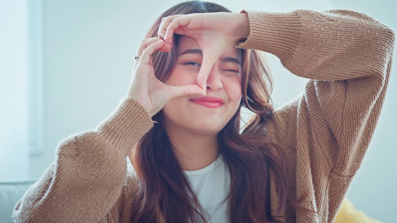 特写快乐的年轻亚洲妇女微笑和显示手标志心形看着相机。健康心脏健康人寿保险，爱心慈善，志愿社会工作。视频素材