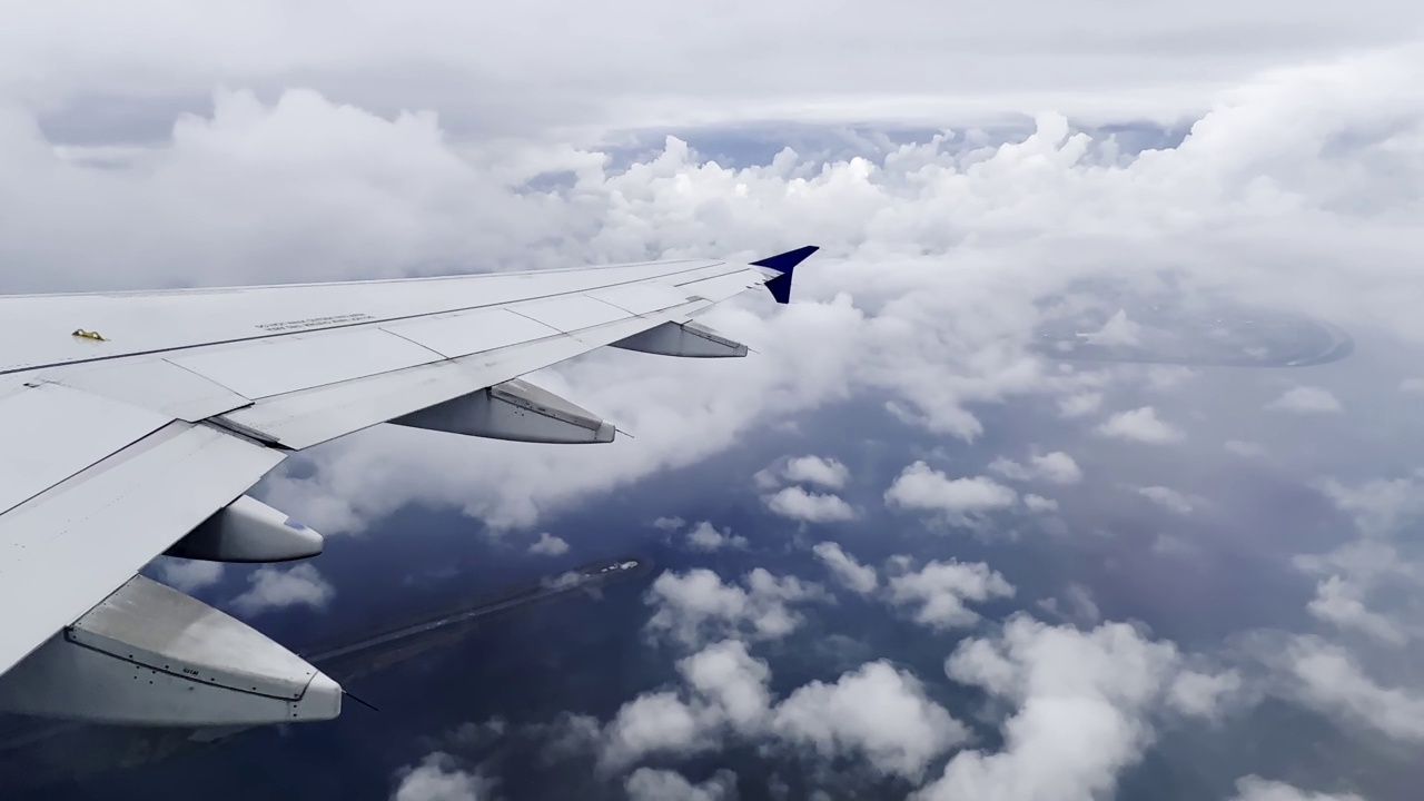 空客A320飞机机翼上的乘客在丹麦上空飞行，穿过多云的天空。旅游和航空运输的概念视频素材