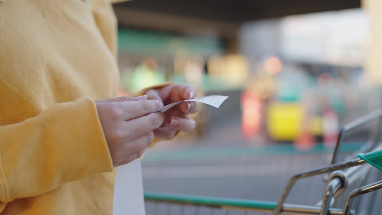 近手妇女检查金额账单在一个杂货店推车。视频素材