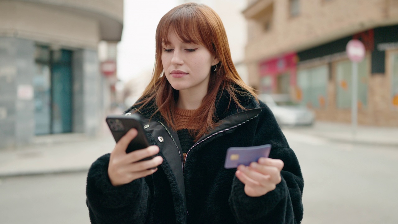 年轻女子在街上使用智能手机和信用卡视频素材