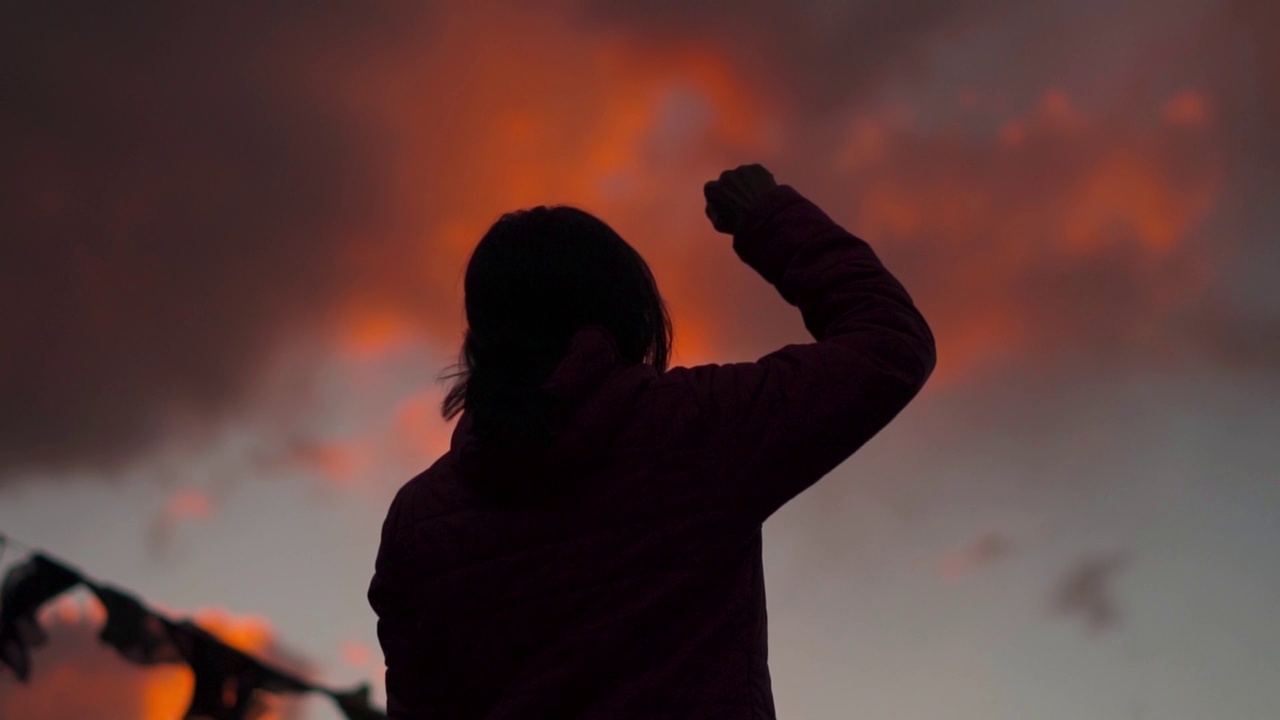 一个女孩在美丽的夕阳前举起手臂的剪影。成功的背景。女人在她的生活中取得了成功。视频素材