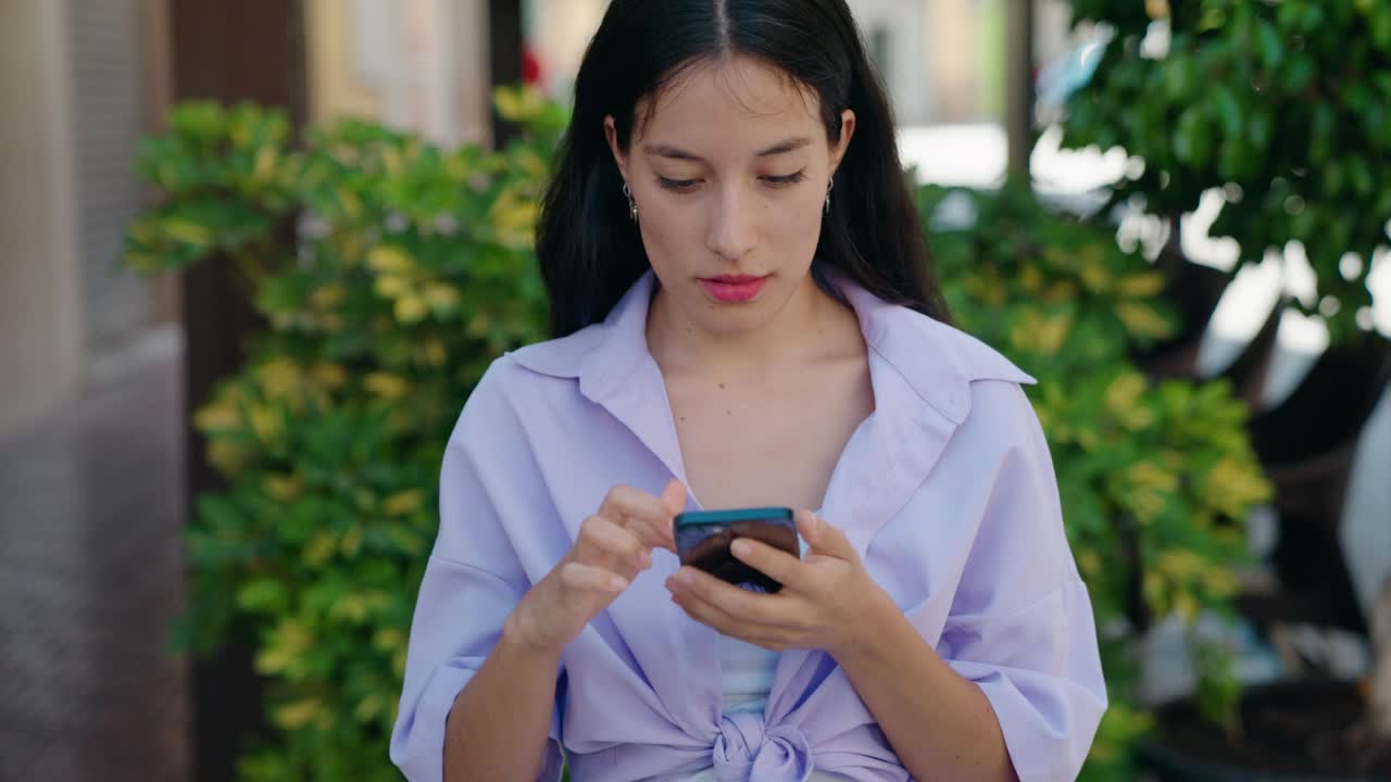 年轻美丽的西班牙妇女使用智能手机与赢家的表情在街上视频素材