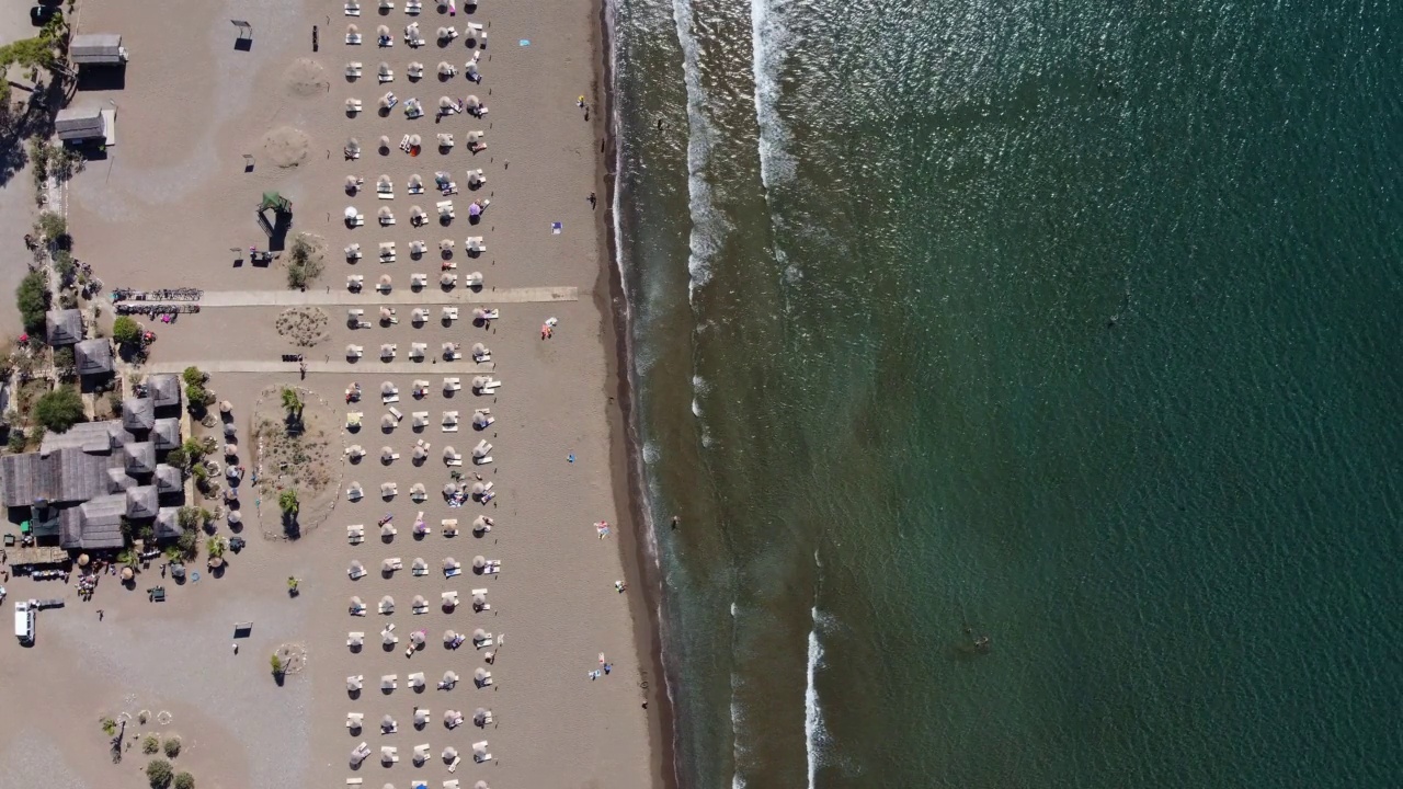 鸟瞰沙滩上的日光浴床、休息室、雨伞。夏季与旅游概念视频素材