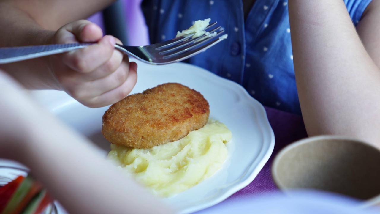 盘子里。孩子吃土豆泥和肉排。视频素材