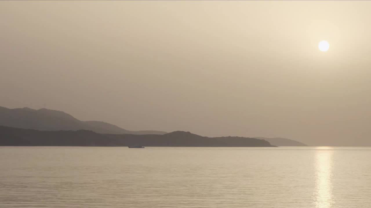 日落时分在海上，橘黄色的太阳高挂在海面上，山峦和海面。Ksamil,阿尔巴尼亚视频素材