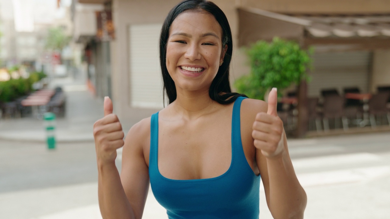 年轻美丽的拉丁女子微笑着，自信地做得很好，在街上竖起大拇指视频素材