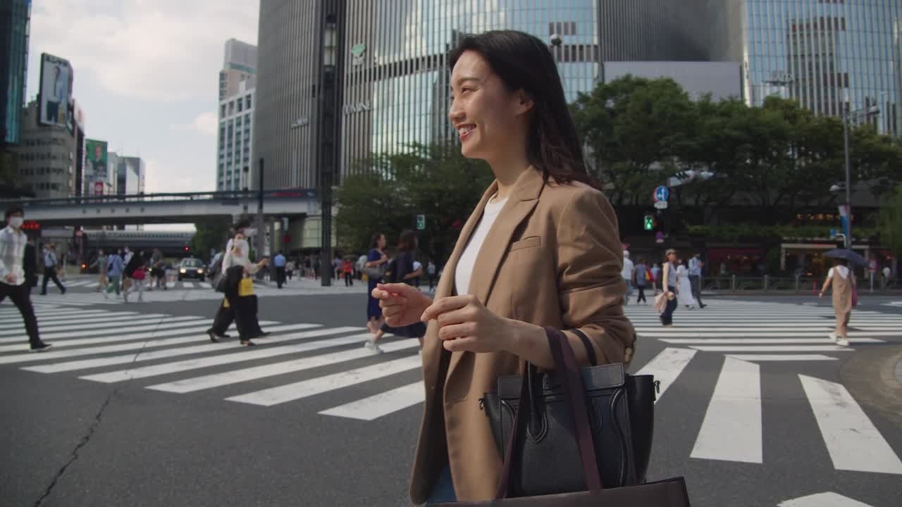 身着商务休闲装的亚洲女子提着购物袋走在东京都视频素材