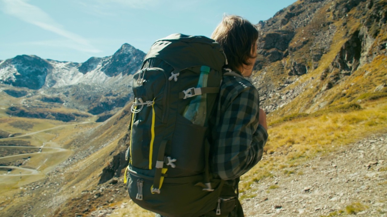 在阳光明媚的日子里，年轻的成年人背着背包爬山旅行冒险视频素材