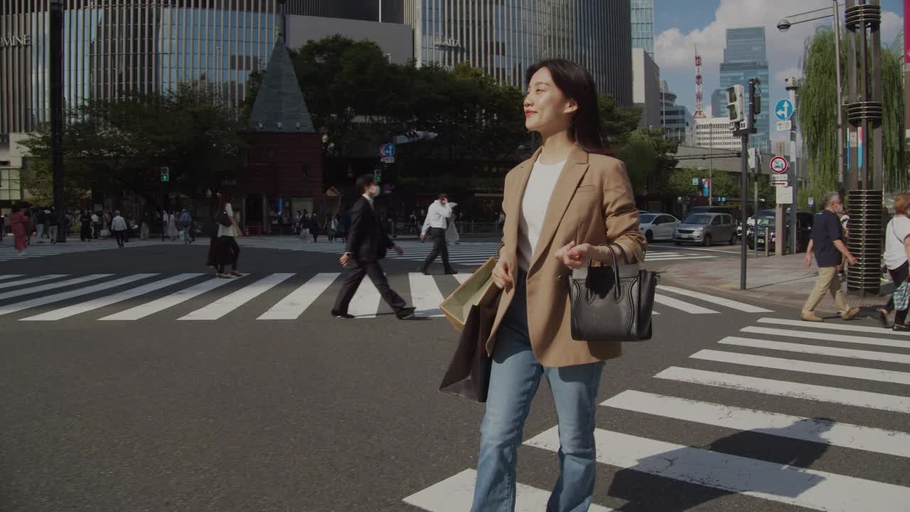 在东京市中心提着购物袋过马路的年轻女子视频素材