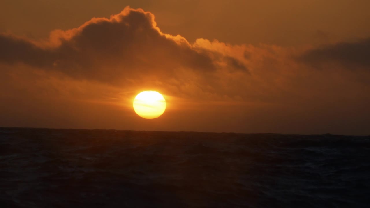 夕阳落在波涛汹涌的海面上，从一艘小船上驶过开阔的大海视频素材