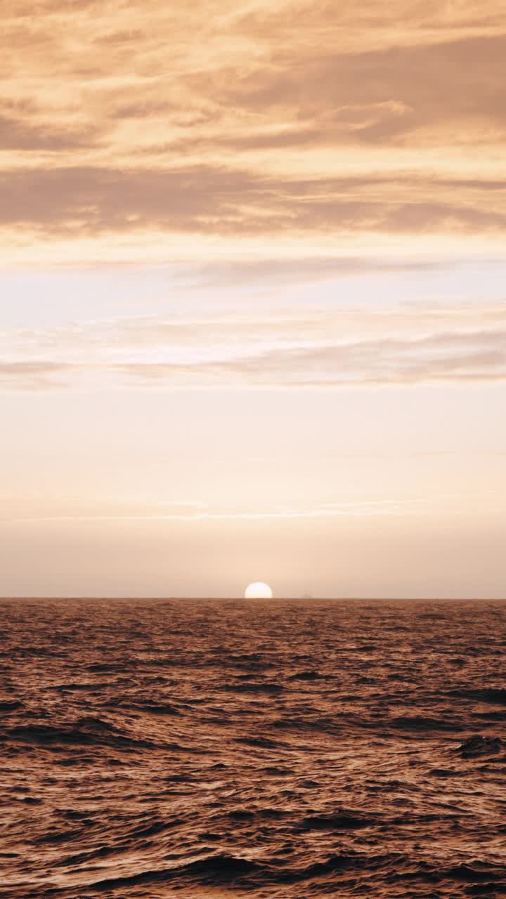 夕阳落在波涛汹涌的海面上，从一艘小船上驶过开阔的大海视频素材