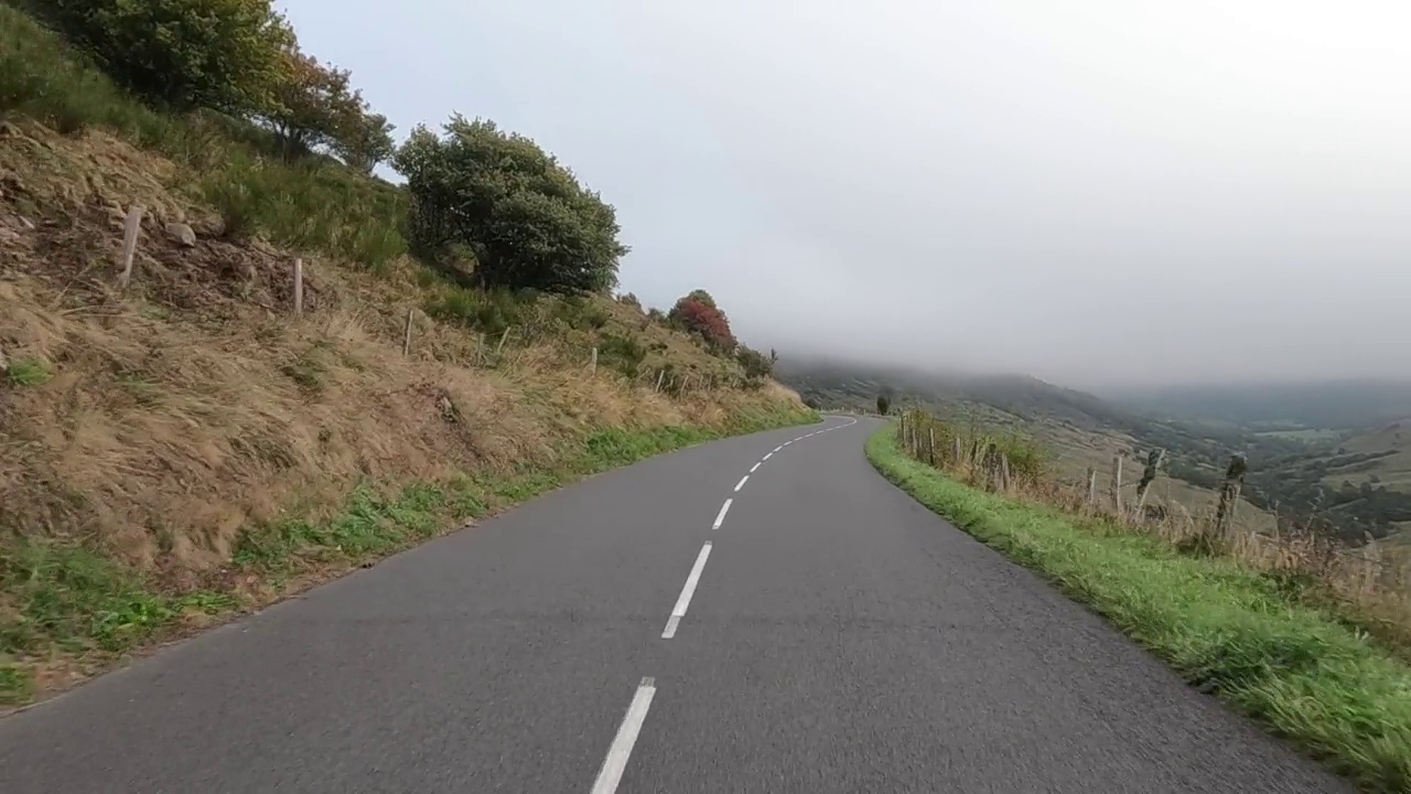 在云中蜿蜒的柏油山路上，从车里看到的景色。视频素材