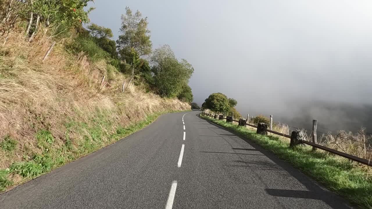 在云中蜿蜒的柏油山路上，从车里看到的景色。视频素材