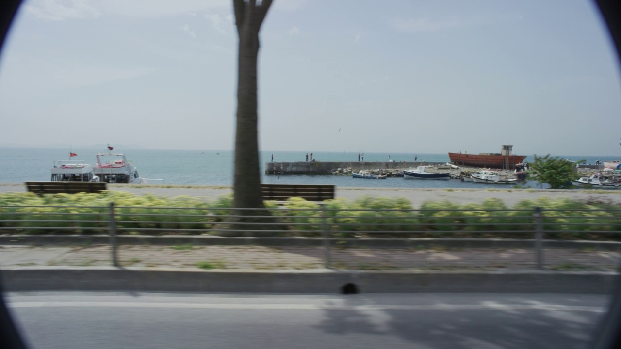 土耳其马尔马拉海沿岸的海滨道路和小路或人行道。可能是肯尼迪大道或者肯尼迪卡德西。在bg中可以看到南伊斯坦布尔海岸警卫队指挥塔。公园的长凳，行人，和树在wa上可见视频素材