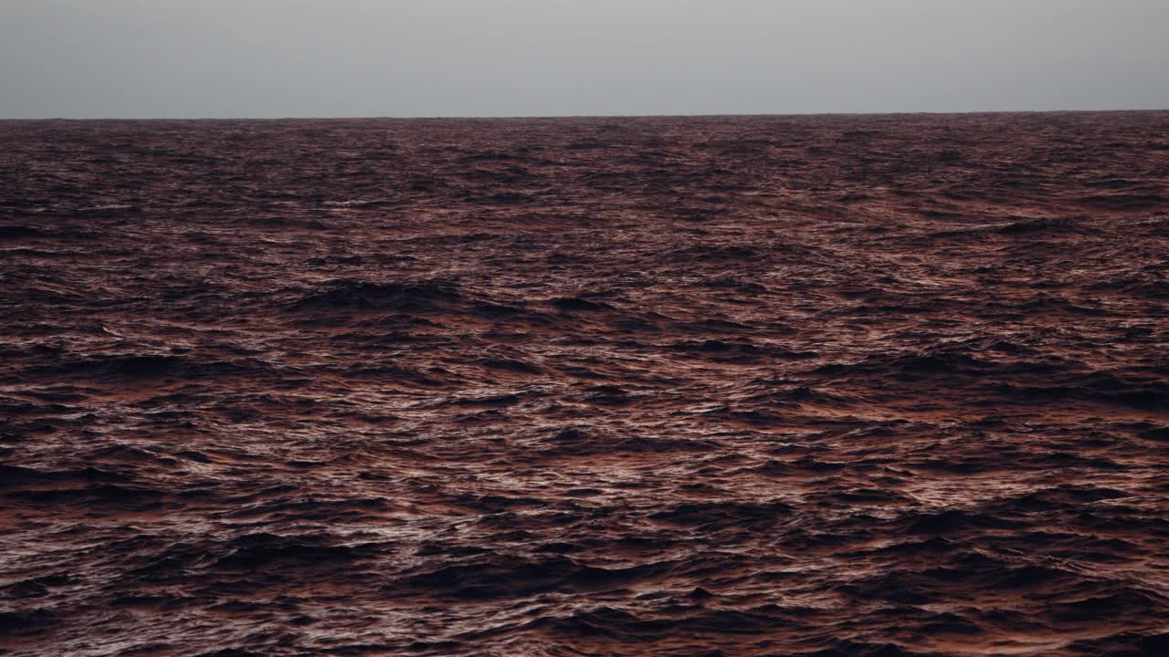 夕阳落在波涛汹涌的海面上，从一艘小船上驶过开阔的大海视频素材