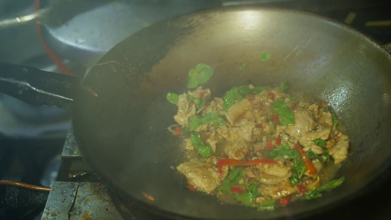 在厨房的炒锅里用泰国罗勒煸炒辛辣的猪肉，Pad Ka prao是最受欢迎的泰国街头小吃之一视频素材