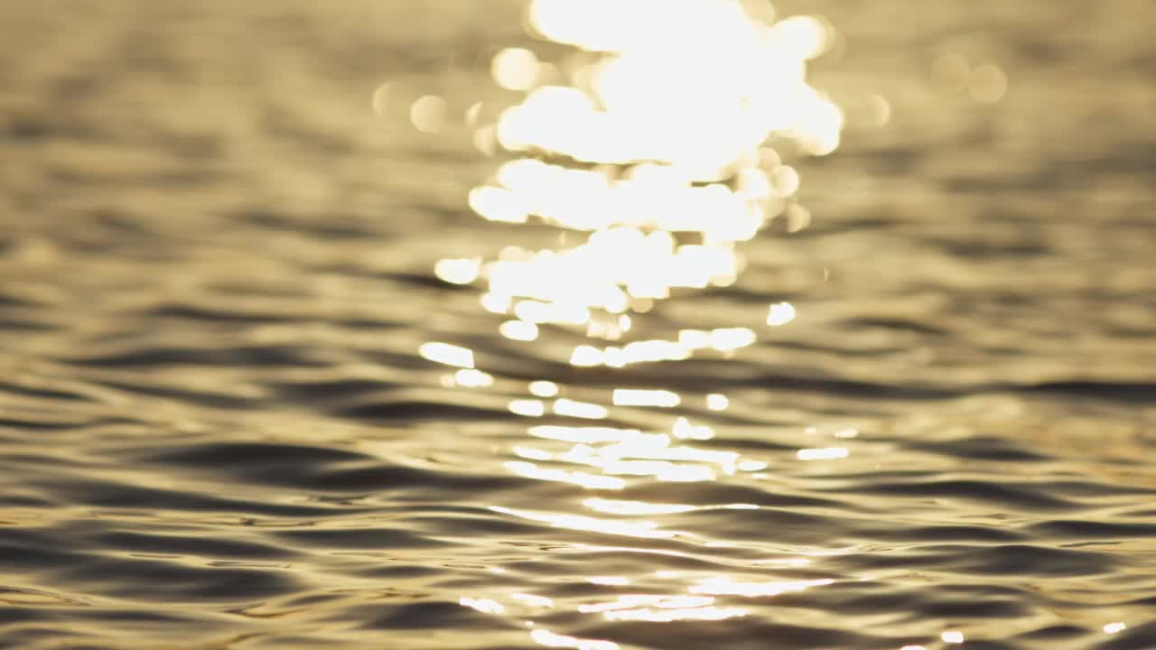 夕阳下海水表面的慢动作镜头。金色阳光在大海或海洋上的反射视频素材