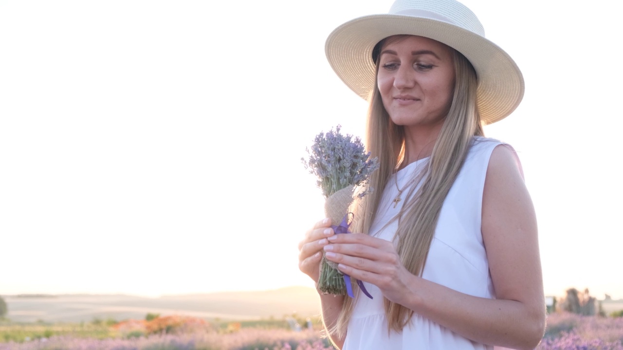 迷人的女人站在明亮的阳光下嗅薰衣草花视频素材