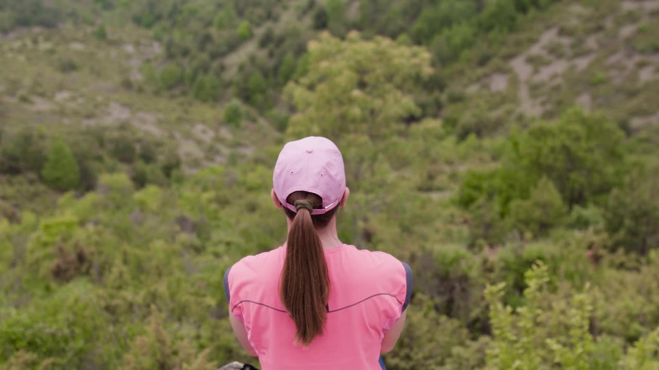 大自然中的远足女孩。坐在岩石上休息，欣赏美丽的风景。视频素材