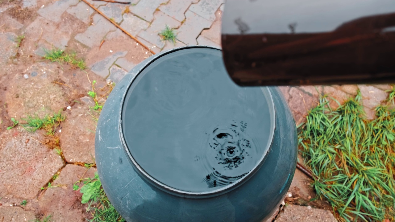 从塑料排水沟滴入溢流桶蓄水池收集雨水视频素材