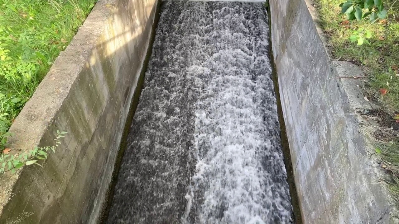 雨水和湖水从混凝土排水渠中汹涌而出。视频素材