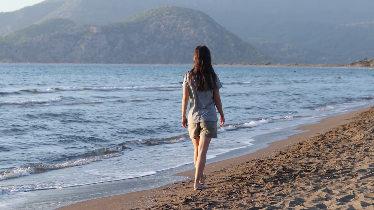 美丽的年轻女子在海滩上散步视频素材