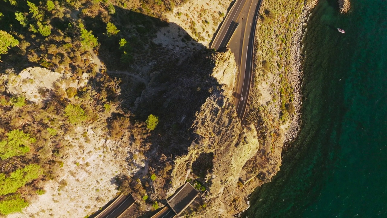 高高的岩石，高速公路上有隧道穿过。阳光明媚的湖岸山地景观。前视图。视频素材