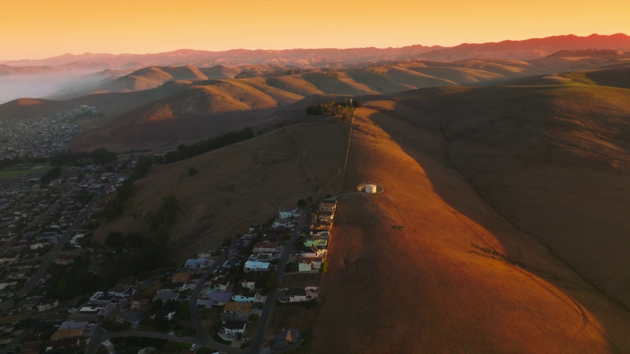 美丽舒适的山脚下城市。落日余晖中光秃秃的山峦的壮观全景。鸟瞰图。视频素材