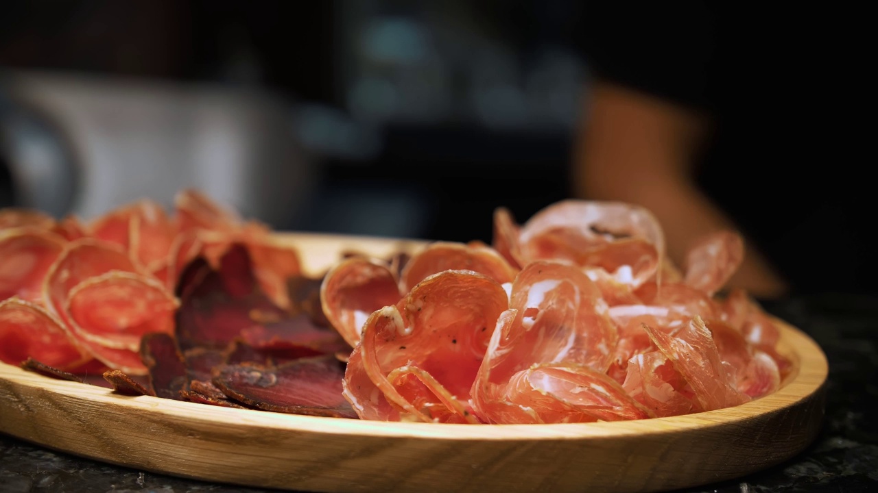 肉开胃菜。jamon。美味的各种肉类开胃菜，熏火腿或火腿肉与迷迭香服务木浅盘。厨师把火腿放在餐板上。视频素材