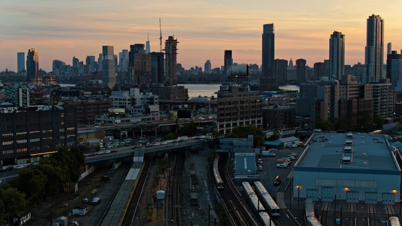 从长岛市的地铁可以看到布鲁克林绿点区(Greenpoint)的建筑建设和猎人角(Hunters Point)的豪华公寓。从东河眺望曼哈顿，日落时分自由塔清晰可见。航拍视频与向后相机运动。视频素材