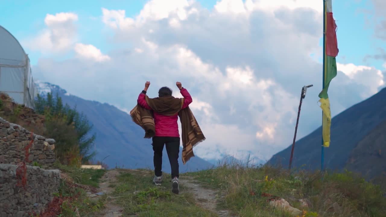 一位印度妇女在美丽的群山和多云的天空前举起双臂。成功的背景。女性在她的生活中取得了成功。成功的徒步旅行者到达顶峰后很高兴视频素材