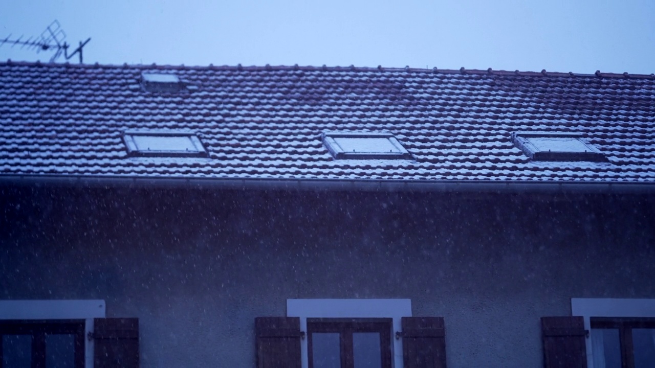 冬季飘落的雪花在屋顶的特写。暴风雪中的传统民居屋顶视频素材