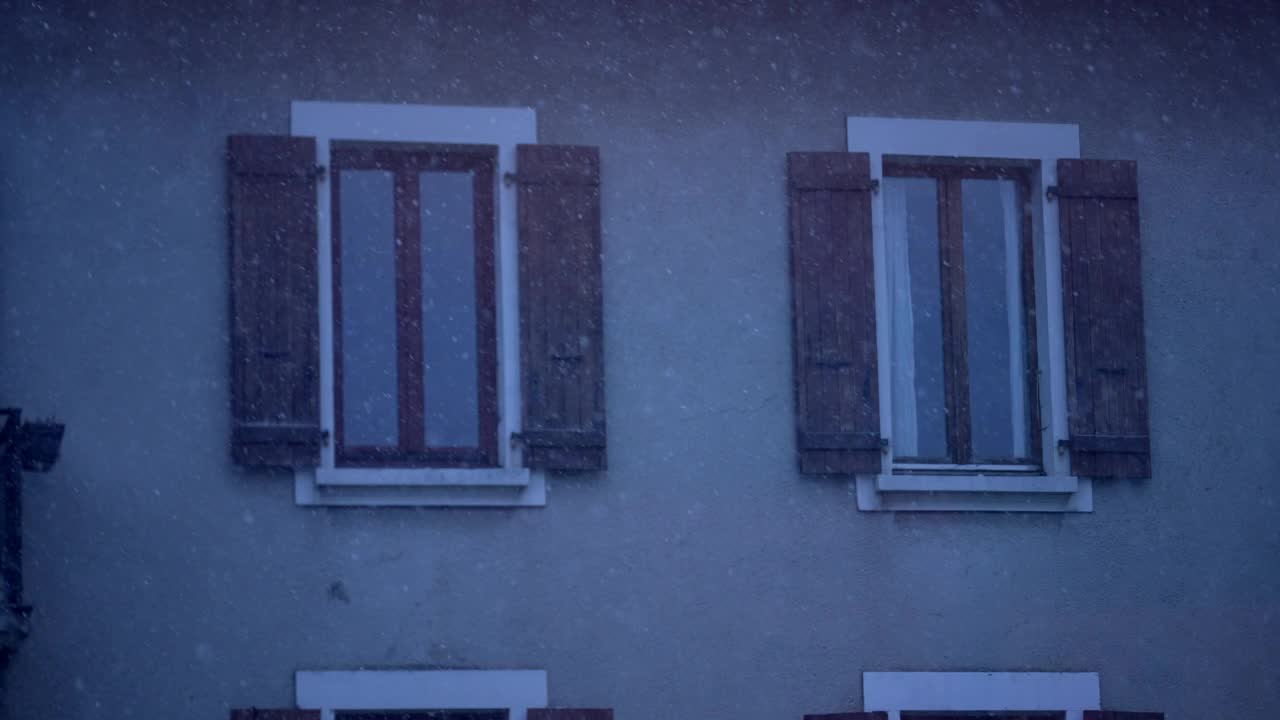 冬天飘落的雪花。暴风雪期间建筑立面外窗的拍摄视频素材