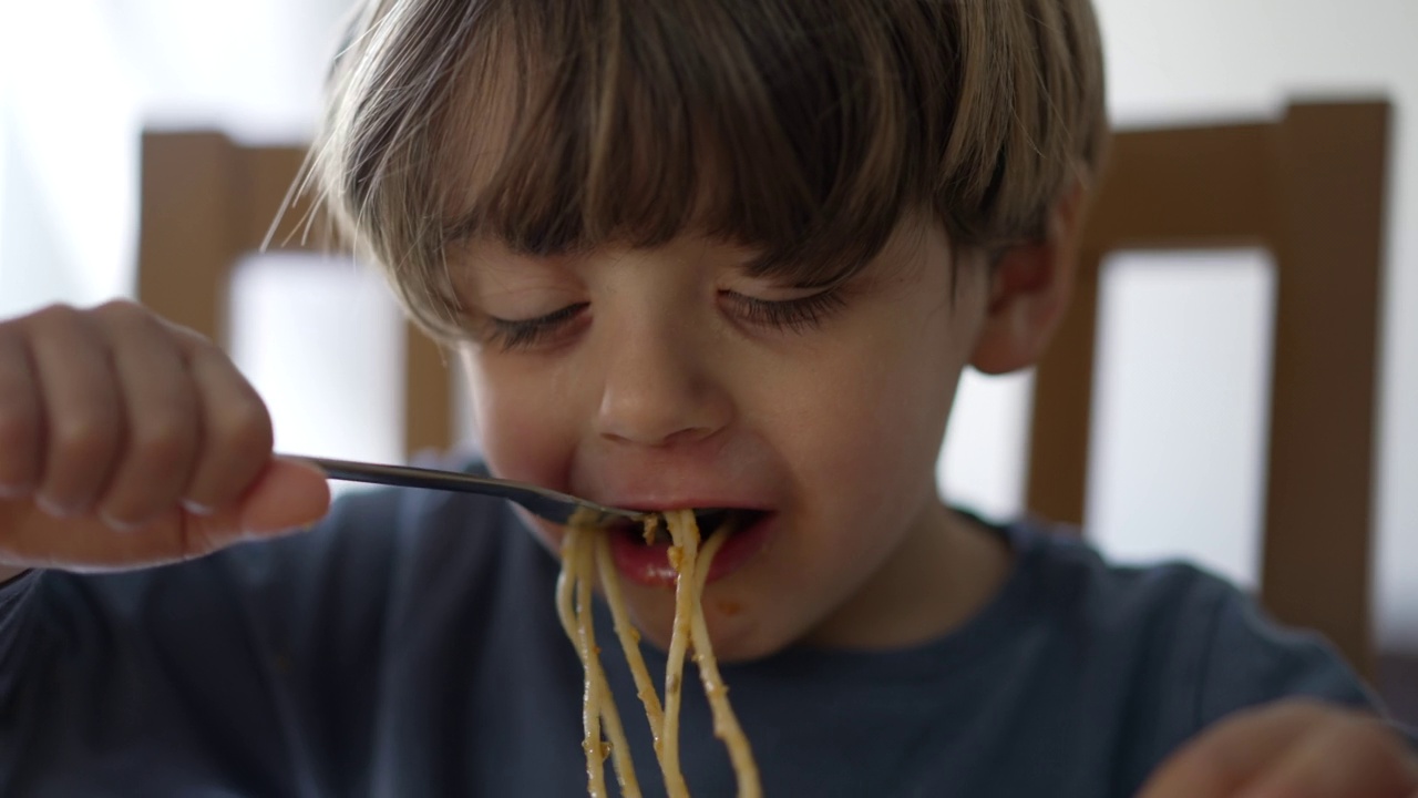 一个小孩用叉子自己吃意大利面。孩子吃午餐视频素材