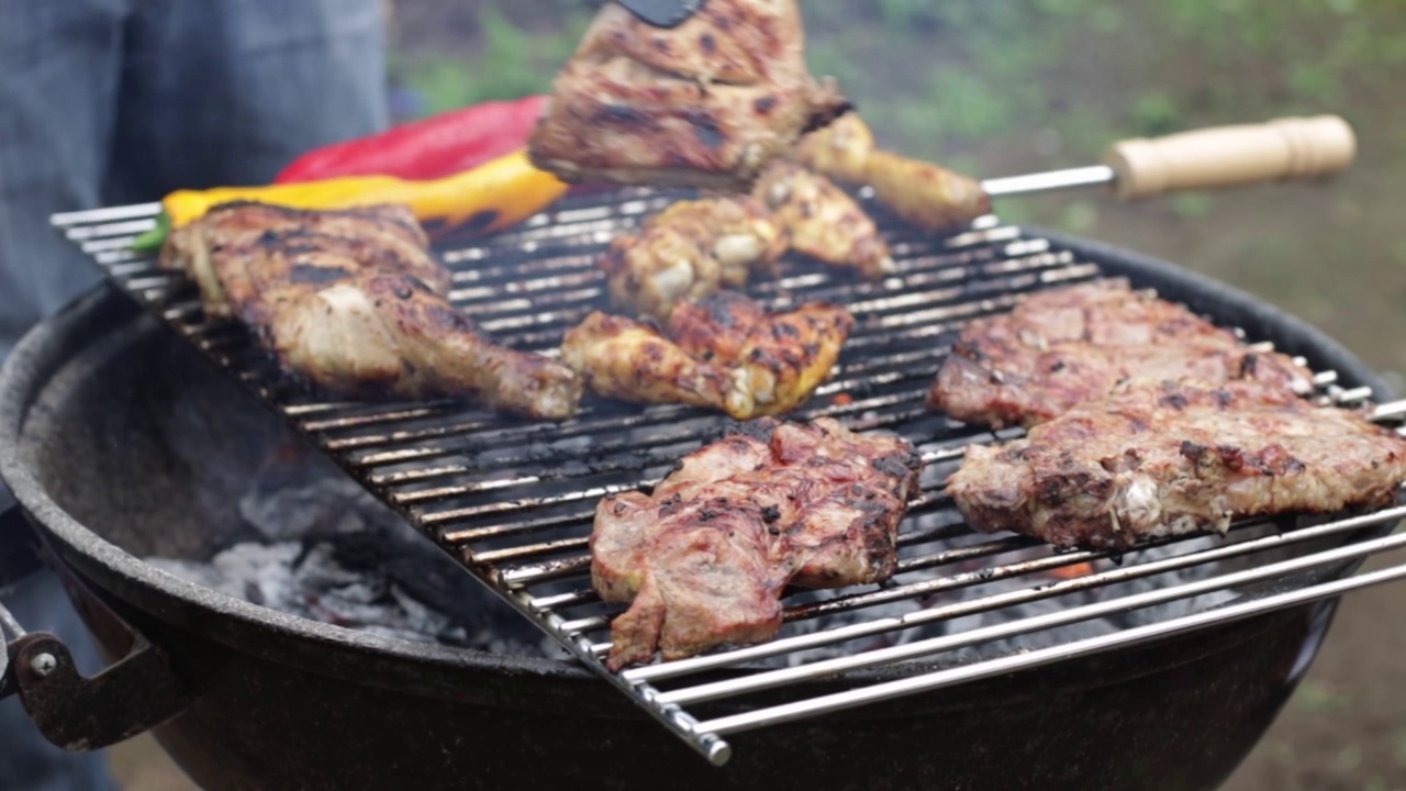 一名男子用火钳翻动烤肉排。视频素材