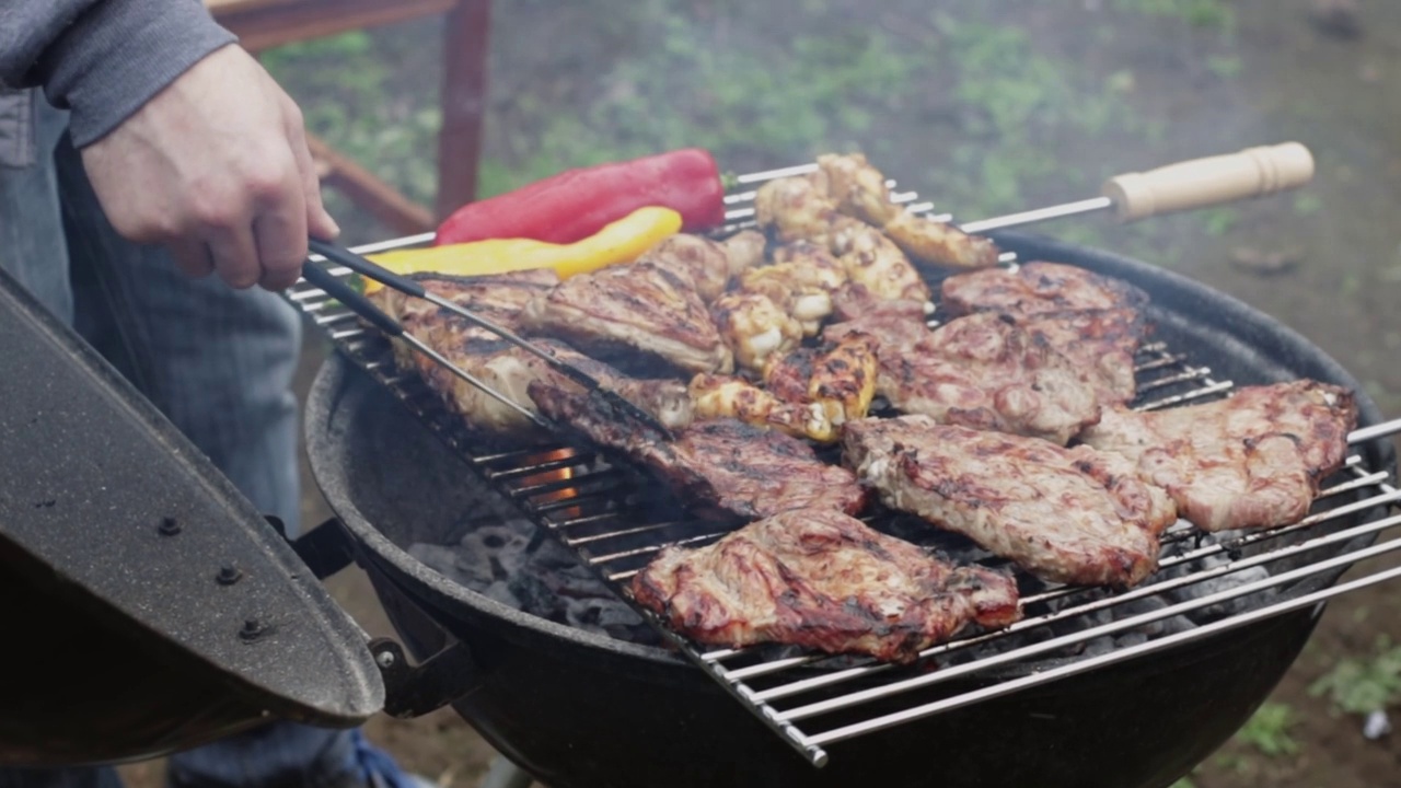 一名男子用火钳翻动烤肉排。视频素材